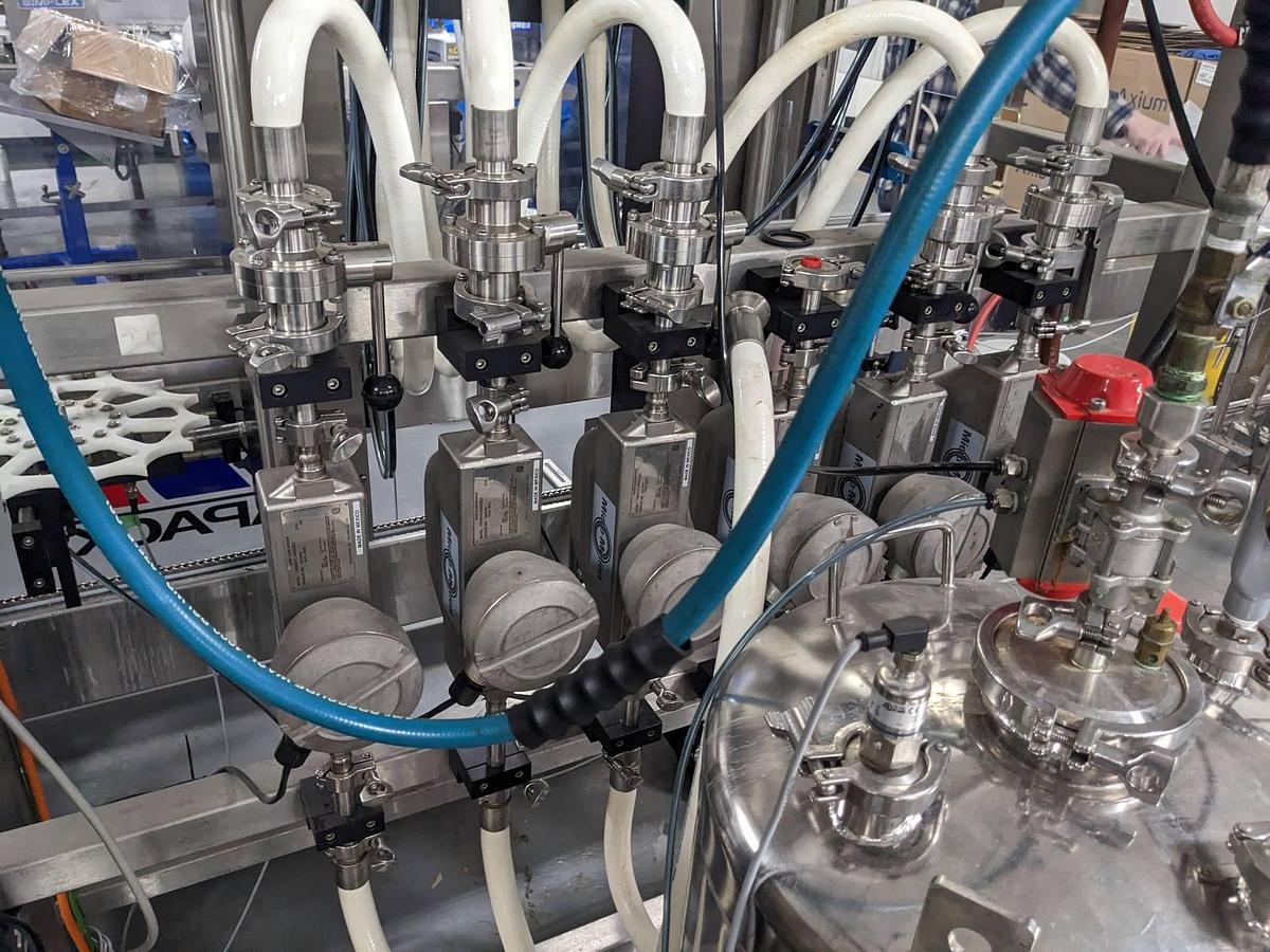 Used Apacks Six Head Automatic Mass Flow Meter Pressure Filling Machine, with conveyor