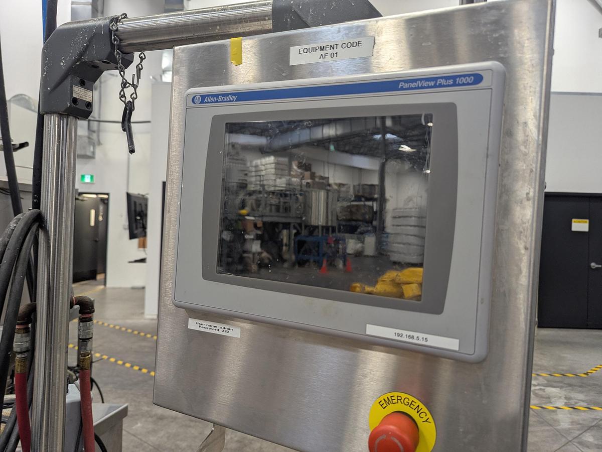 Used Aesus 6-Head Filling Line with Descrambler. Labeler, Filler, Capper, Induction Sealer & Accumulation Table