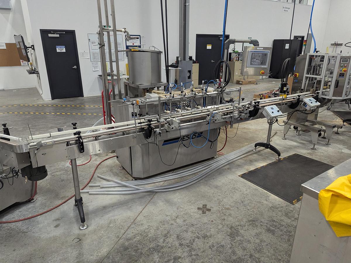 Used Aesus 6-Head Filling Line with Descrambler. Labeler, Filler, Capper, Induction Sealer & Accumulation Table
