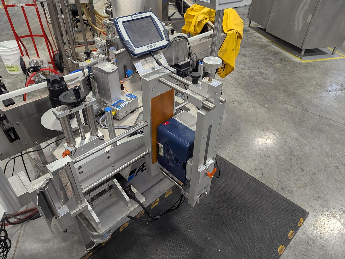 Used Aesus 6-Head Filling Line with Descrambler. Labeler, Filler, Capper, Induction Sealer & Accumulation Table