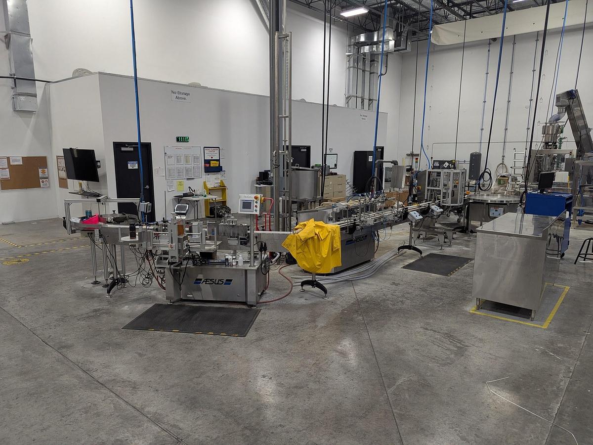 Used Aesus 6-Head Filling Line with Descrambler. Labeler, Filler, Capper, Induction Sealer & Accumulation Table