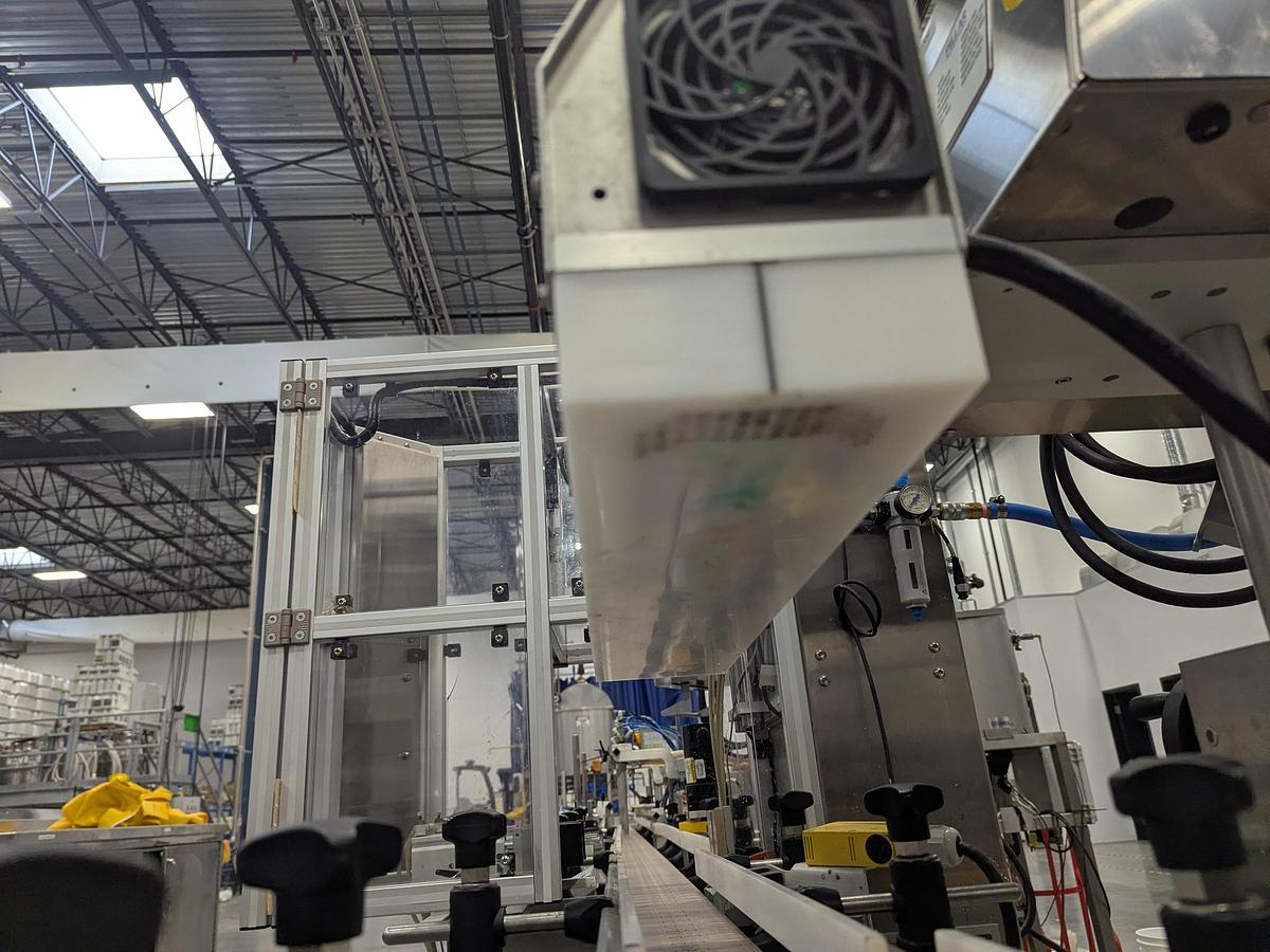 Used Aesus 6-Head Filling Line with Descrambler. Labeler, Filler, Capper, Induction Sealer & Accumulation Table