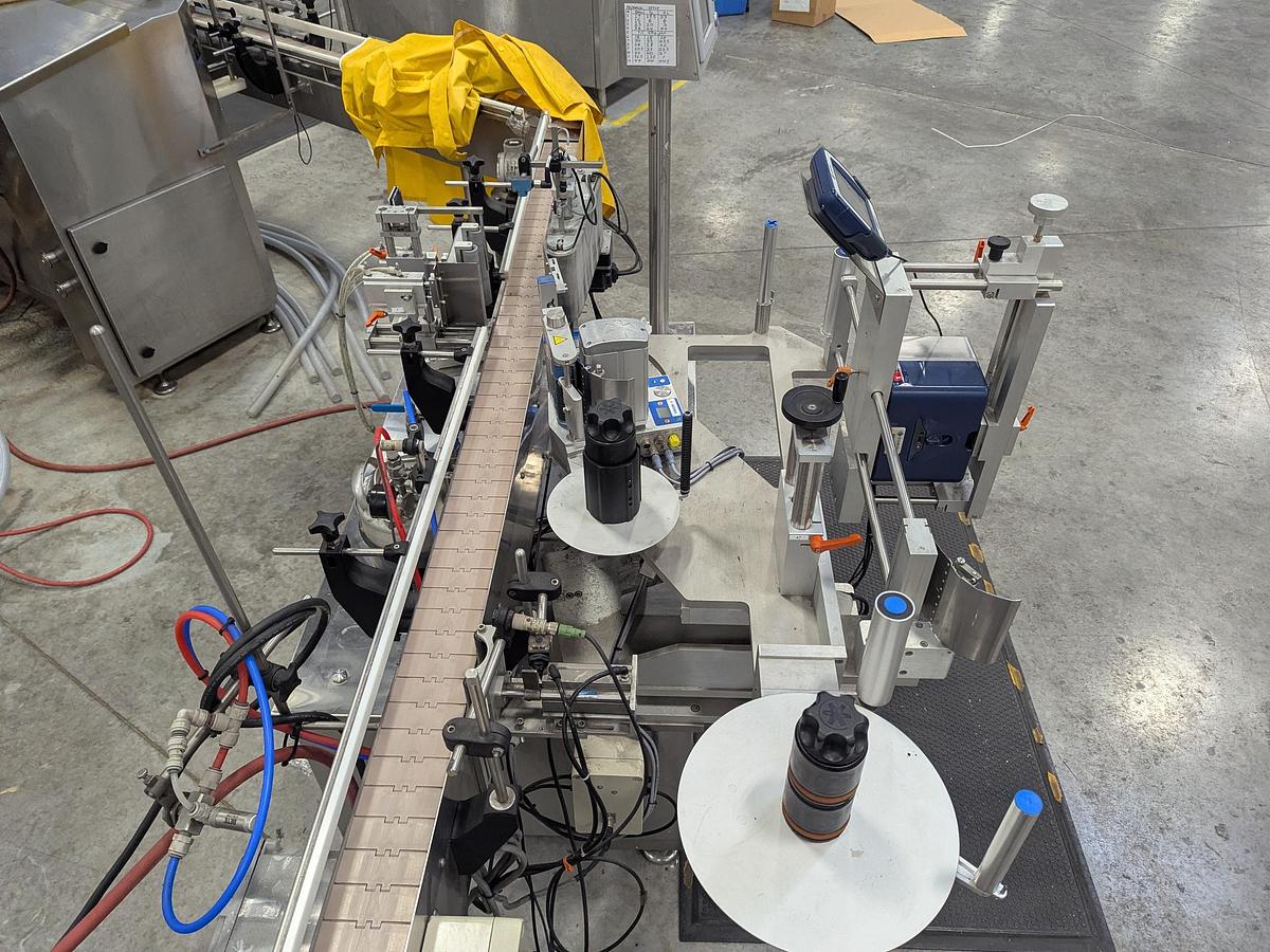 Used Aesus 6-Head Filling Line with Descrambler. Labeler, Filler, Capper, Induction Sealer & Accumulation Table