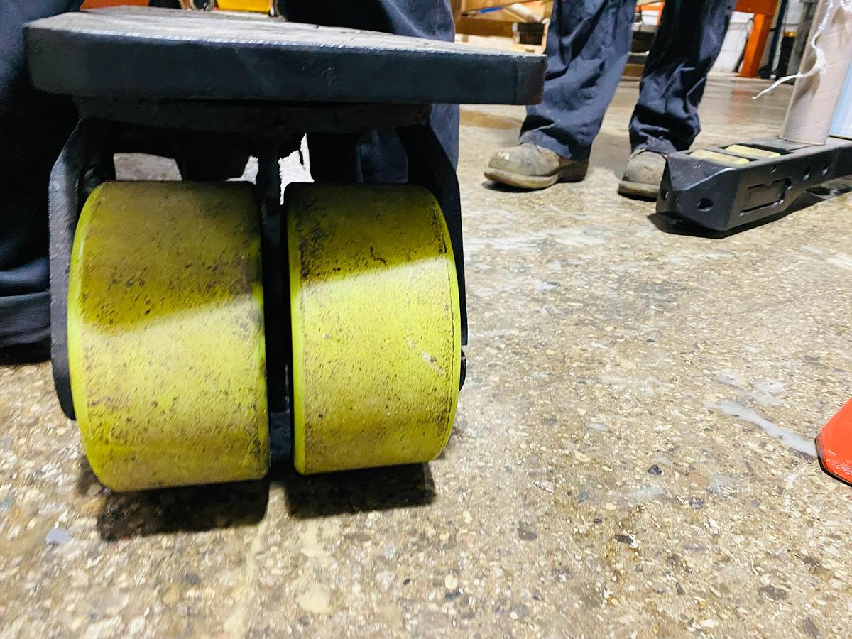 Close-up of front legs on Raymond EASI 4D-R45TT electric reach truck showing newly installed poly caster wheels and directional steering assembly during Brampton deployment