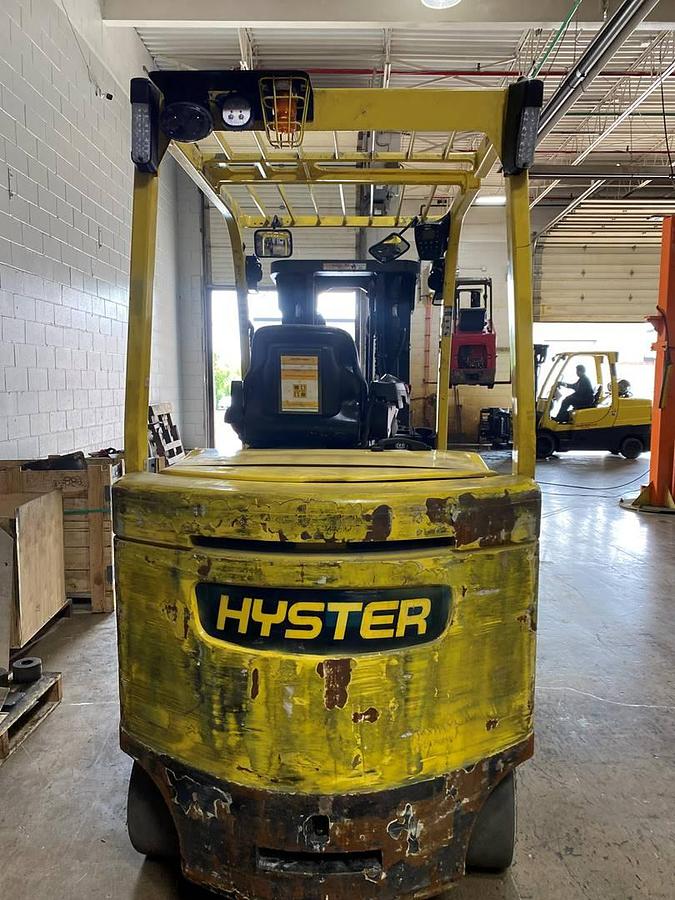 Rear side view of refurbished 2019 Hyster E120XN electric forklift showing rear chassis, solid tires, and CSA certification decal during Ontario deployment.