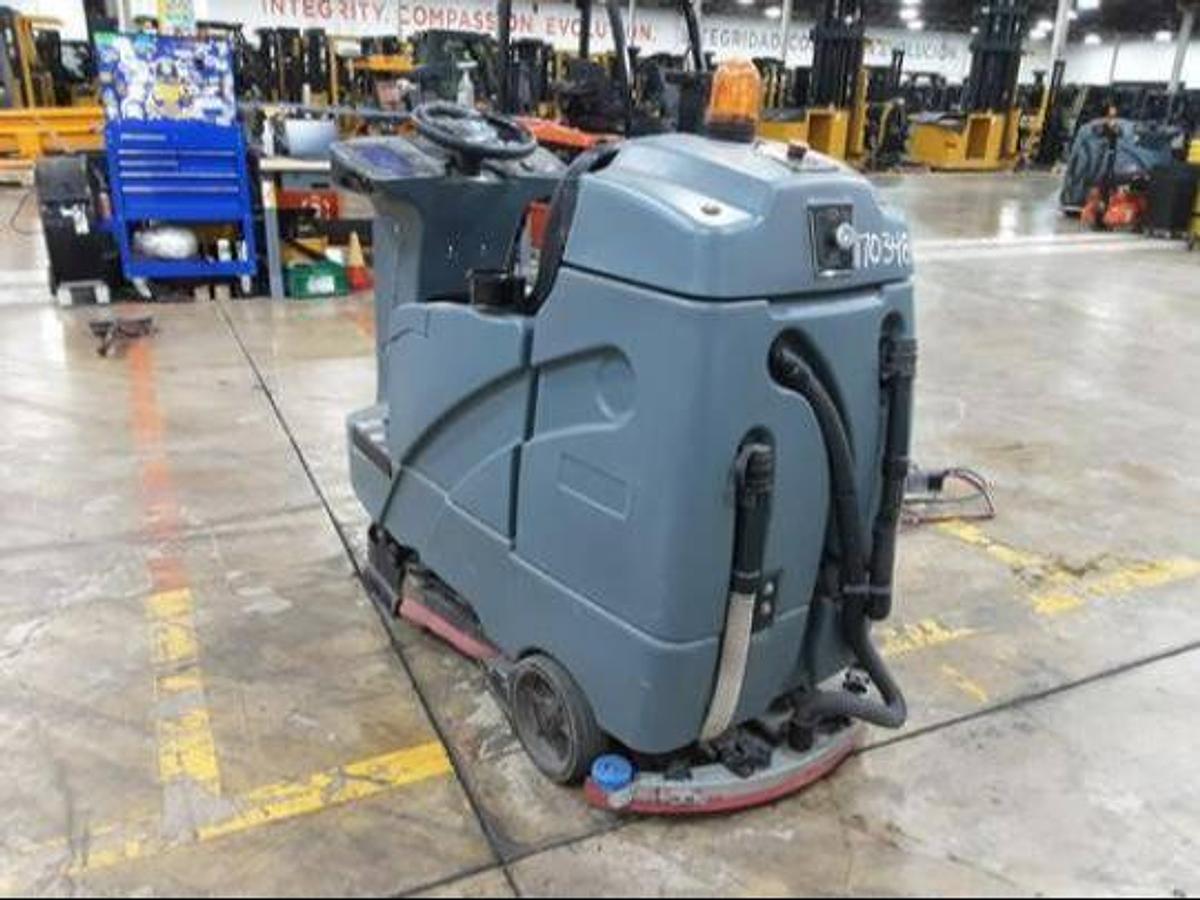 Rear side view of refurbished 2019 Factory Cat RS25 electric rider sweeper‑scrubber showing rear chassis, 24 volt battery compartment, and CSA certification decal during Brampton deployment.
