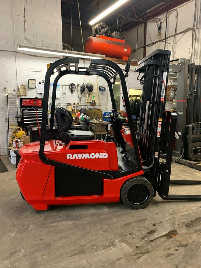 Opposite side view of refurbished 2006 Raymond RTW35 electric 3-wheel sit-down forklift showing battery compartment, rear tire, and CSA decal during Ontario deployment