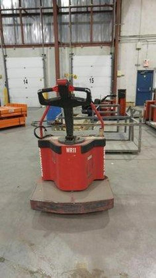 Rear view of refurbished 1996 Raymond 112-FRE60L electric walkie/rider pallet jack showing tiller arm, control head, and flip-down rider platform during Ontario deployment