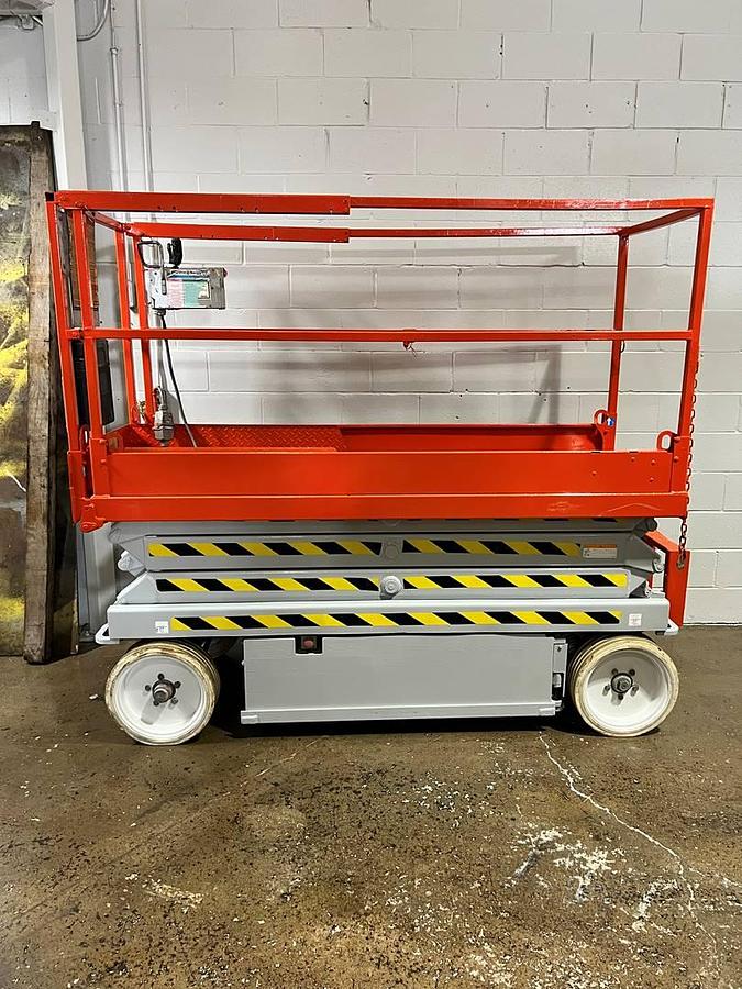 Side view of refurbished 2012 Skyjack SJ3220 electric scissor lift showing 26 ft working height, slab chassis, and CSA certification decal during Brampton deployment.