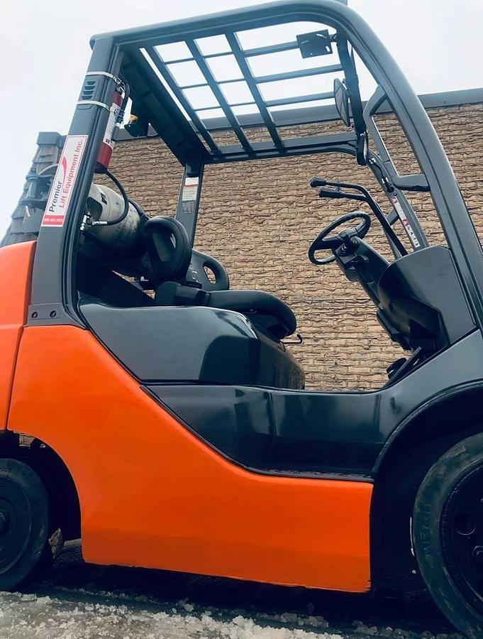 Front side view of refurbished 2013 Toyota 8FGCU25 LP gas forklift showing truckers mast, 42" forks, and solid tires during Brampton deployment
