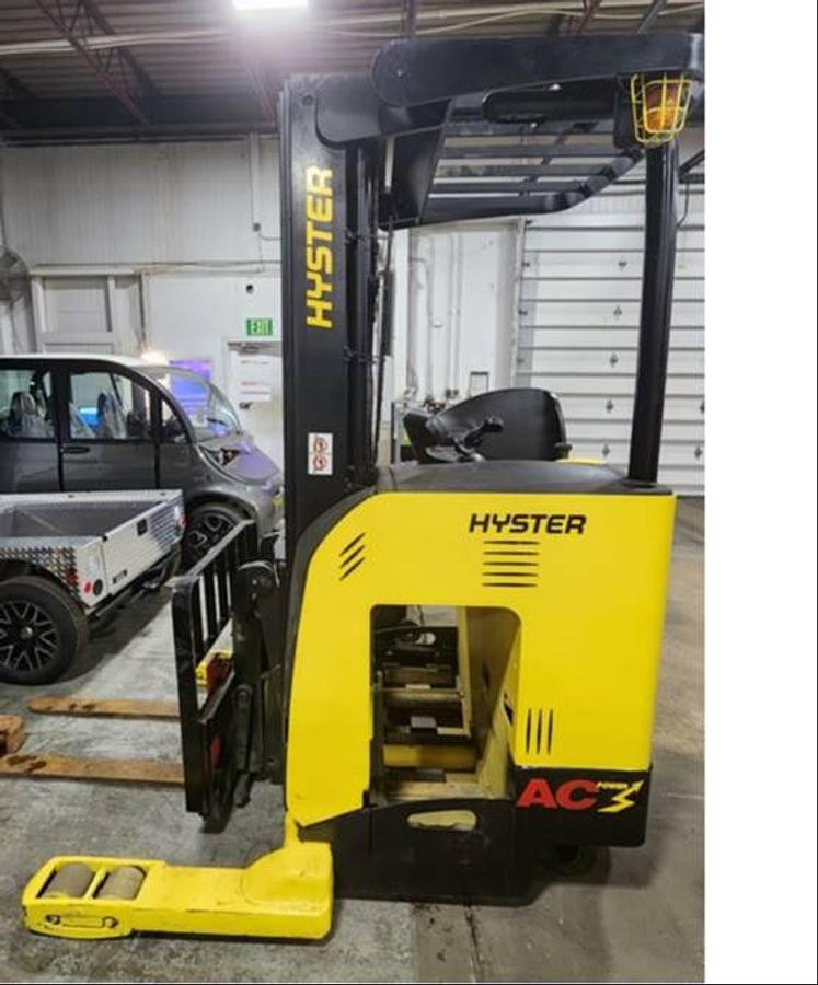 Side view of refurbished 2018 Hyster NR040EB electric reach truck showing 203" mast, 42" forks with load backrest, cushion tires, and CSA certification decal during Ontario deployment.