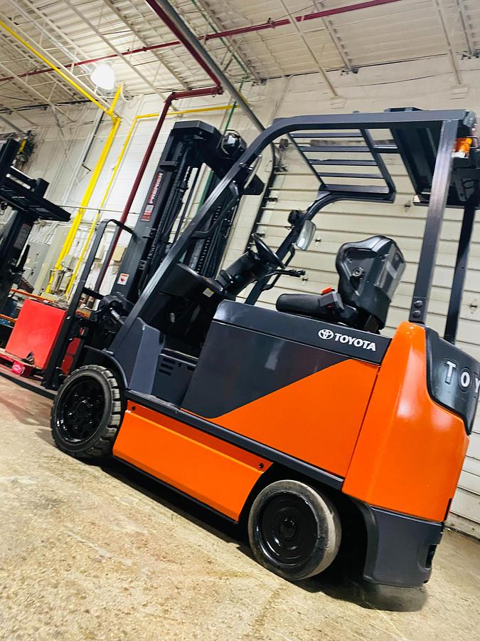 Rear side angle view of 2020 Toyota 8FBCU32-EE electric forklift showing counterweight, triple mast profile, and EE/CSA decals during Brampton deployment