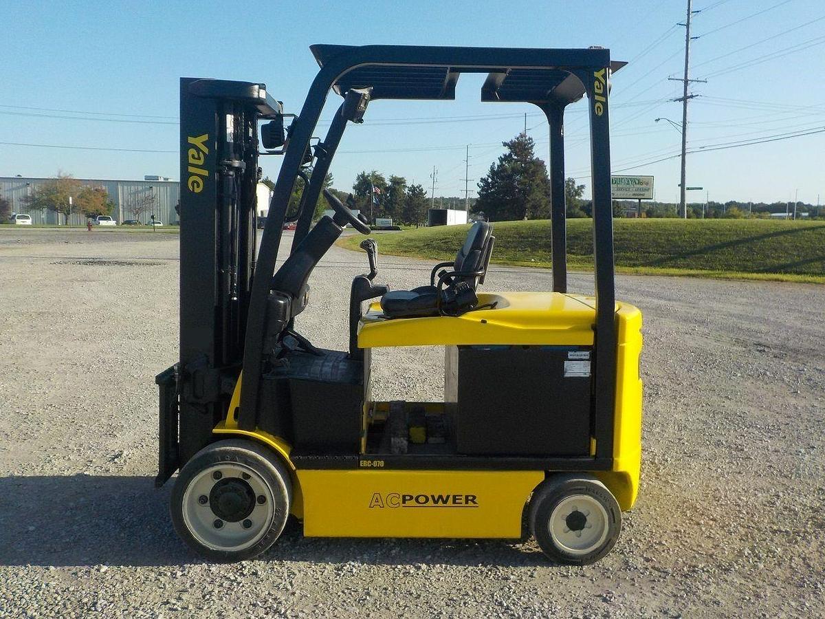 Opposite front side view of refurbished 2012 Yale ERC070 electric forklift showing mast, forks, operator cab, and cushion tire chassis during Brampton deployment