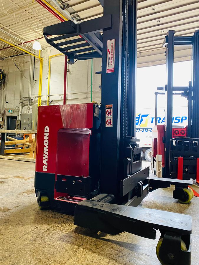 Side profile of 2001 Raymond EASI 4D-R45TT electric reach truck showing directional wheels, mast rails, and narrow aisle chassis during Brampton deployment