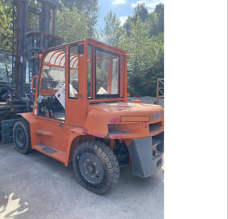 Angled back view from rear to front of Heli CPCD70 outdoor diesel forklift showing counterweight, pneumatic tires, operator cab, and CSA-certified chassis – unit staged in Brampton ON