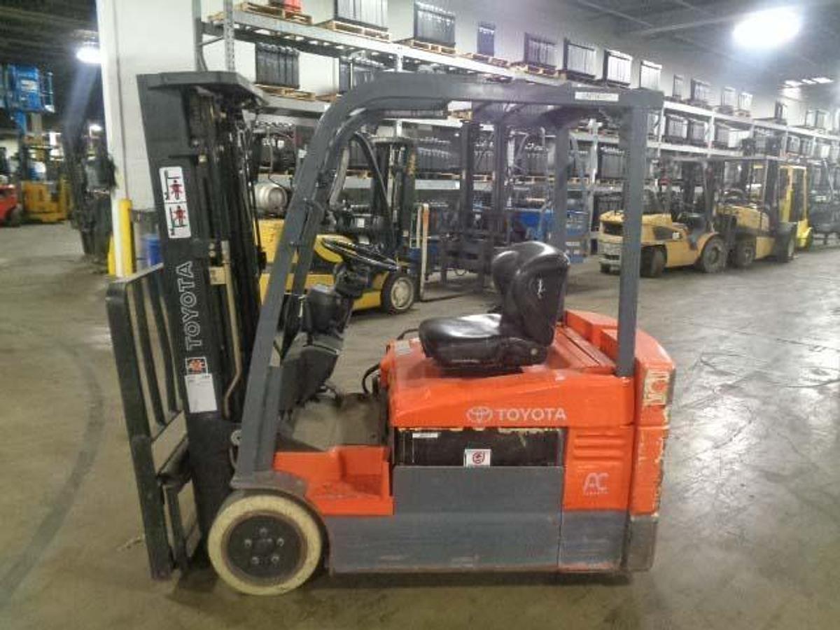Profile view of 2012 Toyota 7FBEU20 electric forklift showing 3-wheel chassis, battery compartment, and mast configuration