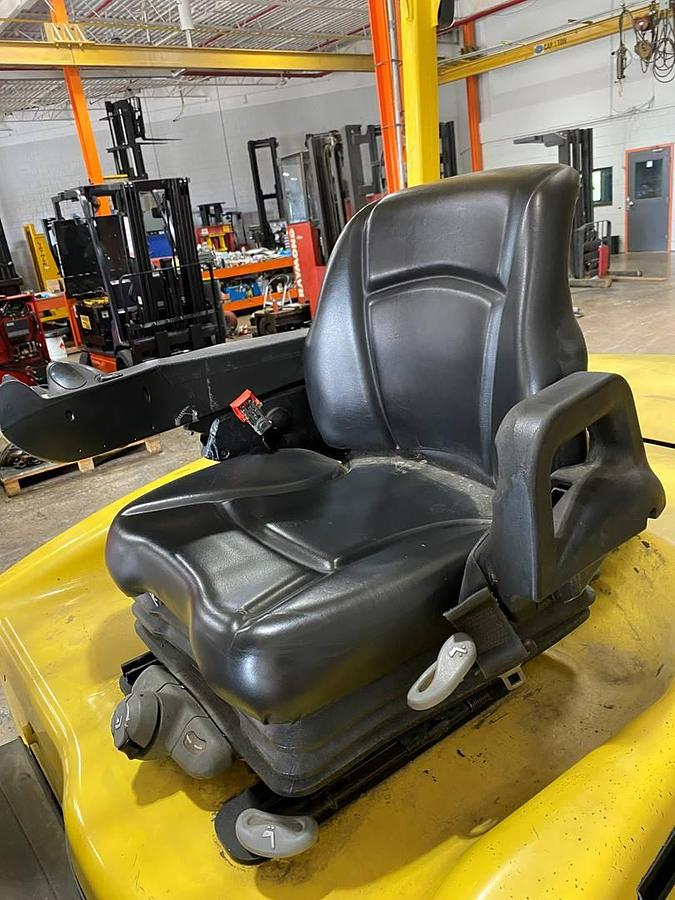 Operator seat of refurbished 2019 Hyster E120XN electric forklift showing seat, steering wheel, and ministick hydraulic controls for 4‑way attachment use, with CSA certification decal during Ontario deployment.