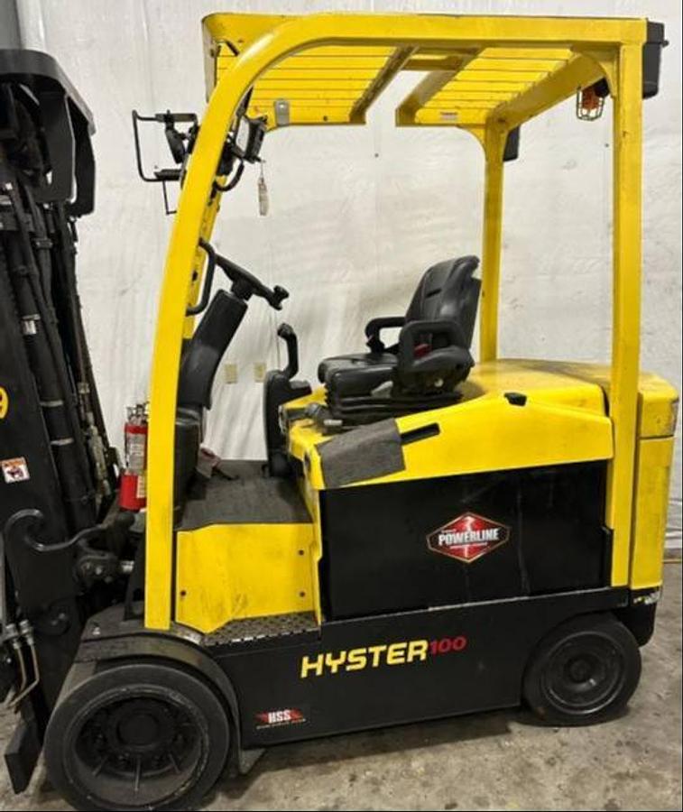 Side view of refurbished 2018 Hyster E100XN electric forklift showing 3‑stage mast, 42" forks, 36V battery compartment, solid tires, and CSA certification decal during Ontario deployment.