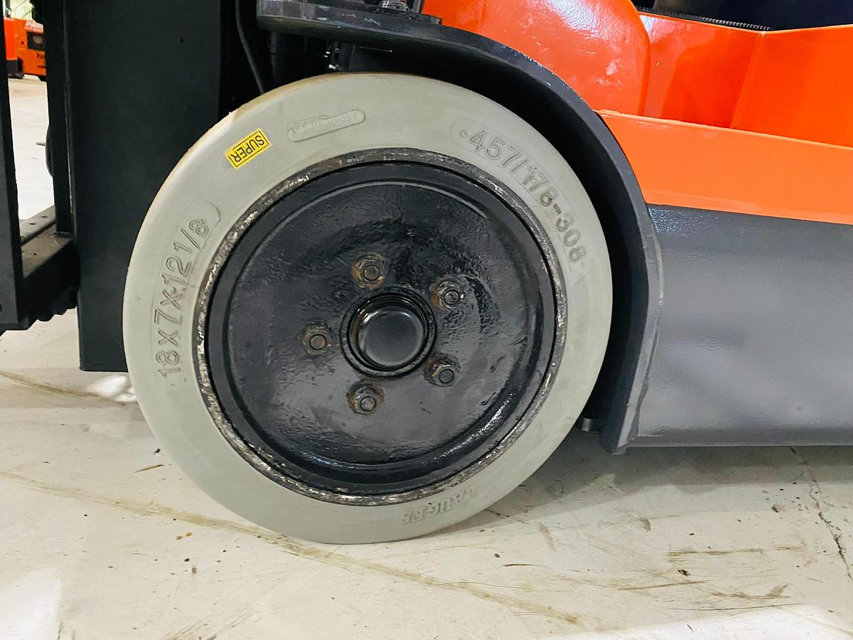 Close-up of non-marking left side drive wheel on 2012 Toyota 7FBEU15 electric forklift showing tread detail and CSA safety markings