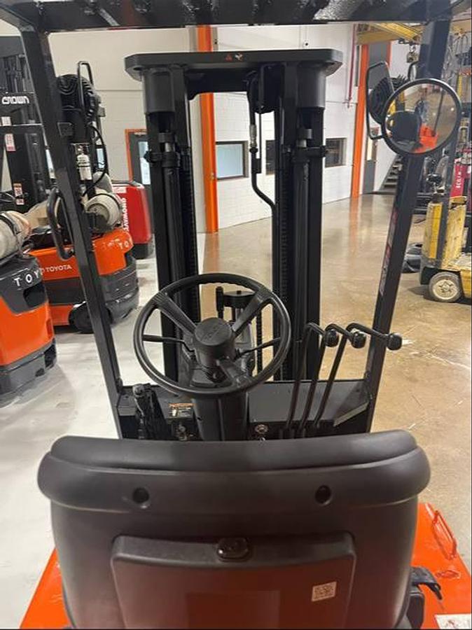 Operator compartment view of refurbished 1996 Toyota 5FBCU15 electric 4-wheel sit-down forklift showing steering column, hydraulic levers, and seat backrest from behind during Ontario deployment
