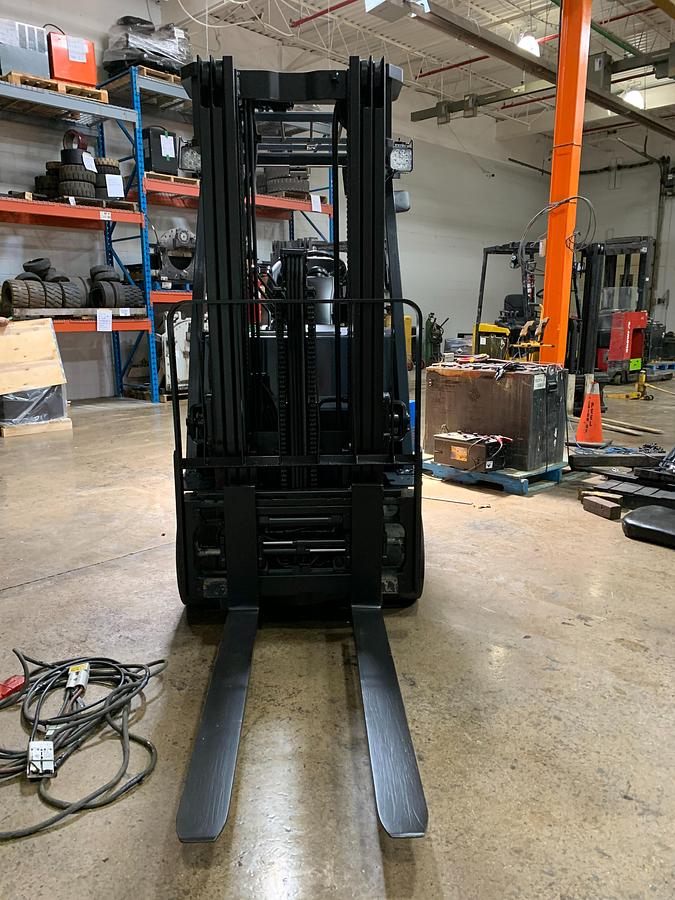 Head-on view of 2017 Toyota 8FBCU25 electric forklift with forks lowered, triple mast extended, and CSA safety markings visible