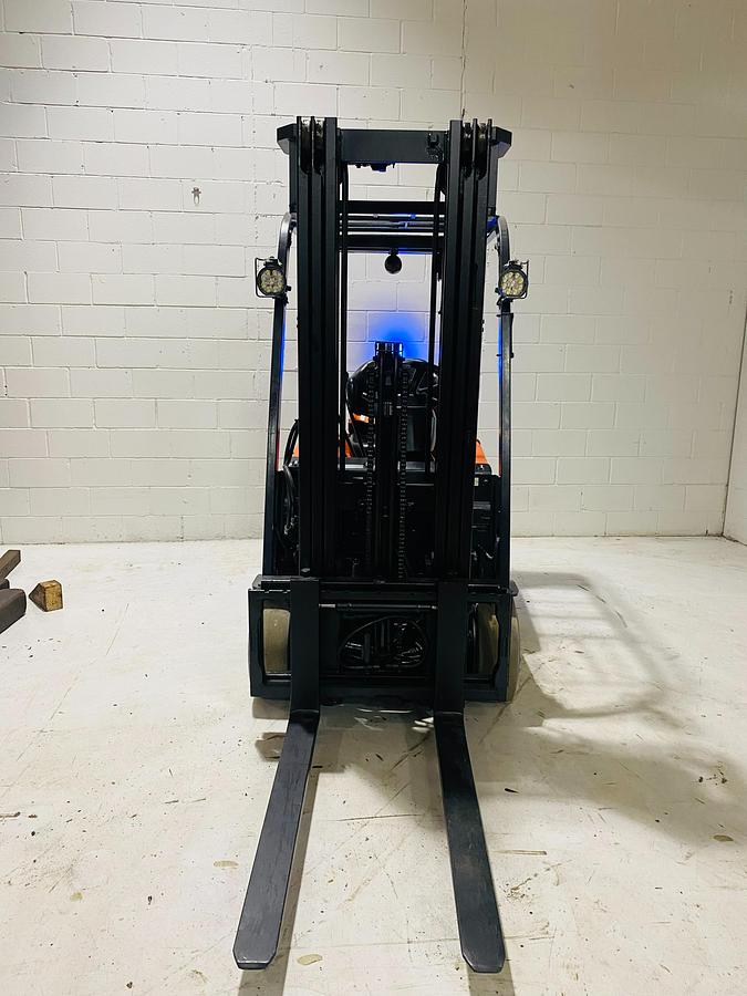 Front view of 2015 Toyota 7FBEU15 electric forklift showing triple-stage mast, extended forks, load backrest, and CSA-certified chassis – unit staged in Brampton ON