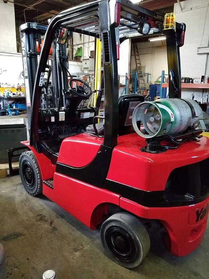 Opposite rear side view of refurbished 2011 Yale GLP050VX LP Gas forklift showing counterweight, cab enclosure, solid pneumatic tires, and CSA certification decal during Ontario deployment.