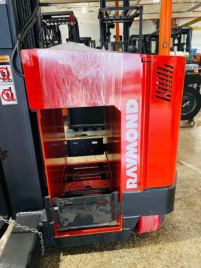 Opposite side close-up of Raymond EASI 4D-R45TT electric reach truck showing open battery compartment, battery rollers, and CSA compliance tag during Brampton deployment