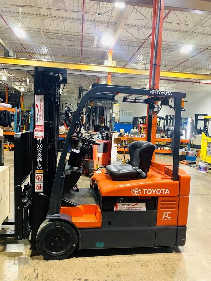 Side view of Toyota 7FBEU20 3-wheel electric sit-down forklift shown chassis only without battery or charger – CSA-certified 4,000 lb unit featuring 189” triple mast, side shift fork positioner, non-marking cushion tires, and 36V AC chassis staged in Brampton ON; battery and charger available separately as extra options new or used – Premier Lift Equipment