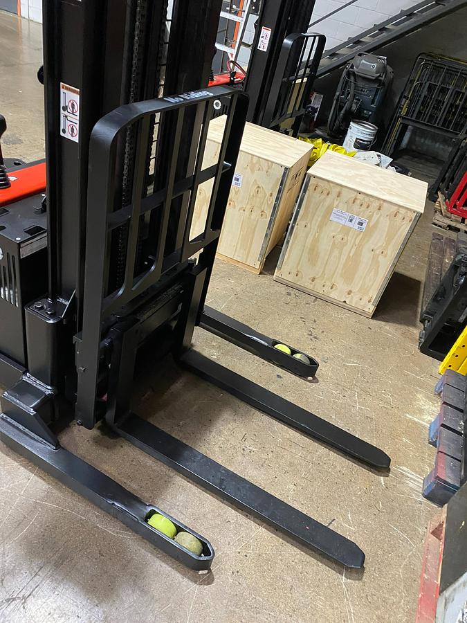 "Angled view of Raymond RSS straddle legs and 42-inch forks for narrow-aisle pallet stacking"