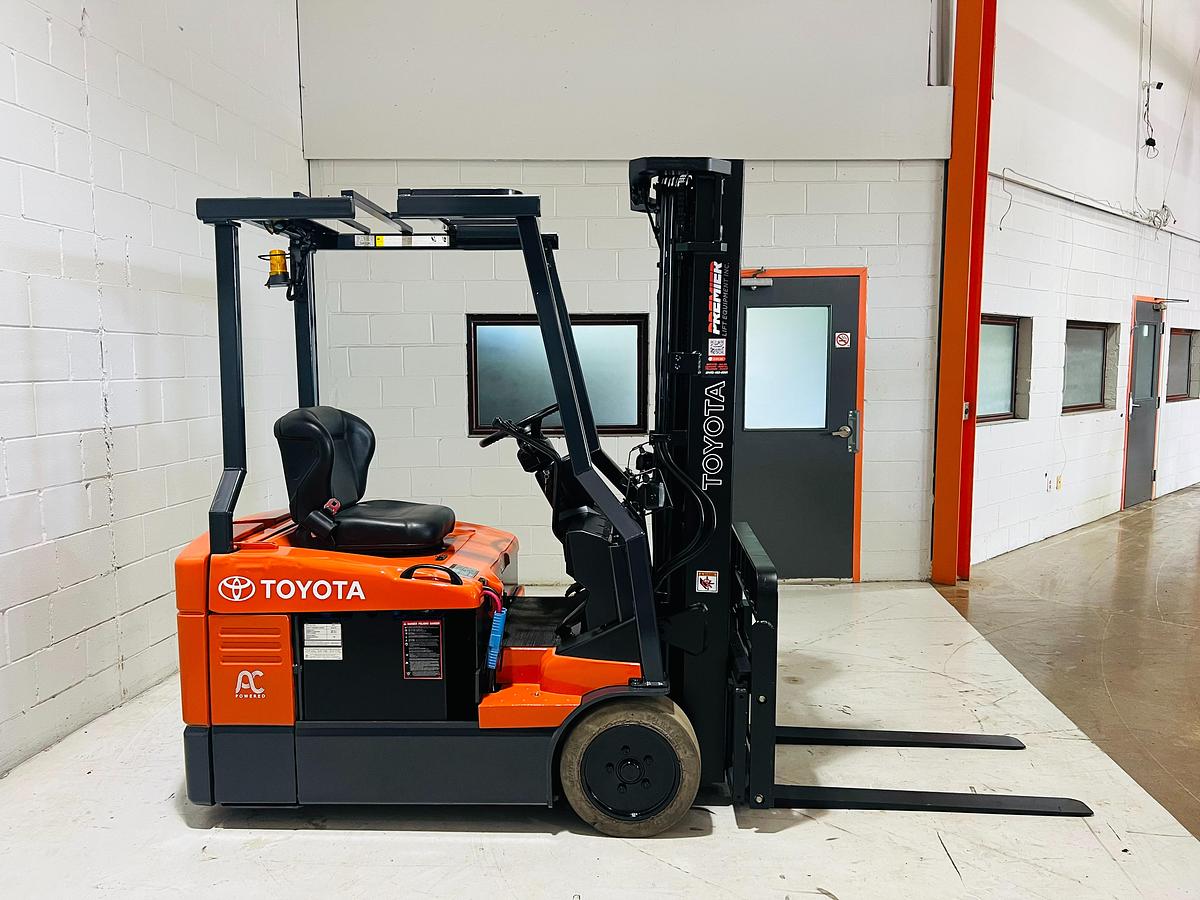Profile view of 2014 Toyota 7FBEU15 electric forklift showing 3-wheel chassis, battery compartment, and trimmed overhead guard for drive-thru racking