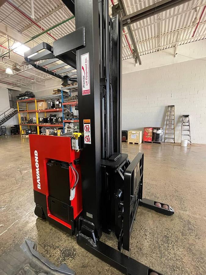 Front side angle of Raymond EASI-DR25TT deep-reach forklift showing 253" triple mast, reach carriage, directional wheels, and narrow aisle chassis during Brampton deployment