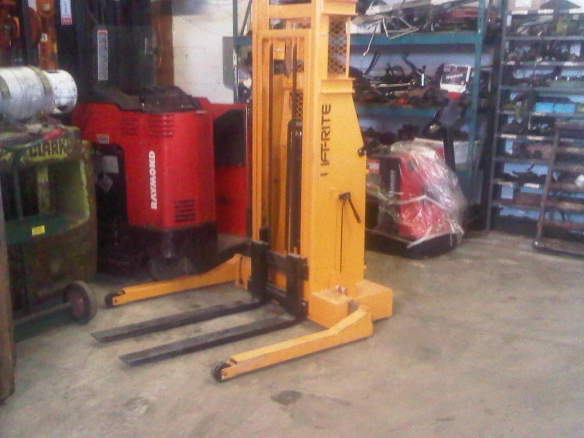 Front angled view of refurbished 2010 Lift‑Rite T90K4024A manual push electric lift stacker showing forks, adjustable straddle legs, battery compartment, and CSA certification decal during Ontario deployment.