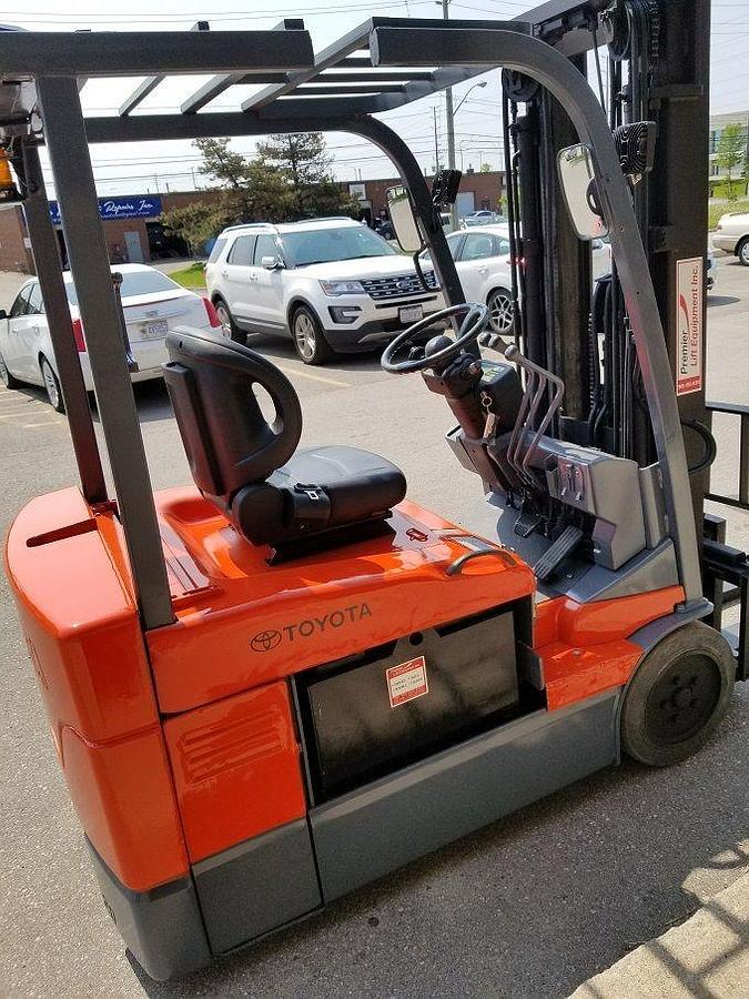 Opposite side view of 2014 Toyota 7FBEU15 electric forklift showing mast rails, CSA decals, and chassis profile during Brampton deployment