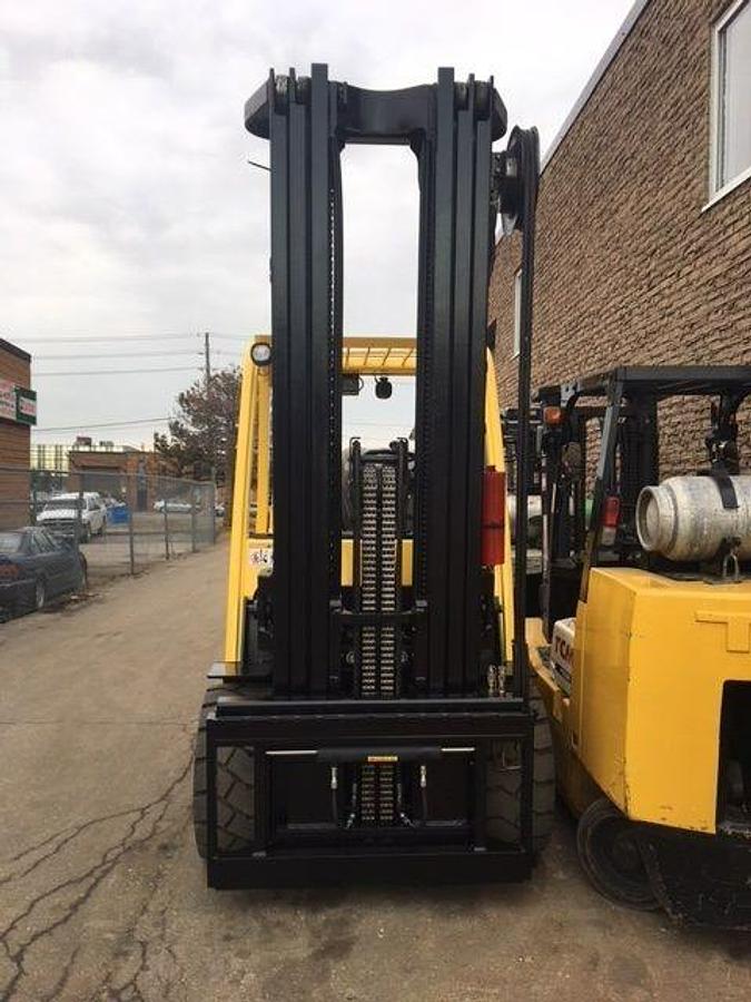 Head-on view of refurbished 2014 Hyster S155FT LPG cushion forklift showing high triple mast, 60" forks, monotrol pedal, and operator cab during Brampton deployment