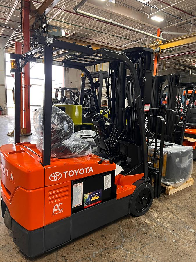 Rear side angle view of 2014 Toyota 7FBEU18 electric forklift showing counterweight, CSA decals, and triple mast profile during Brampton deployment