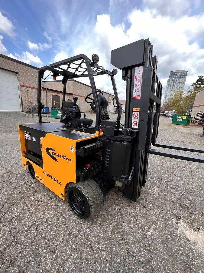Front side angle of Drexel SL-40AC SwingMast forklift showing 250" quad mast, pivoting carriage, directional wheels, and narrow aisle chassis during Brampton deployment