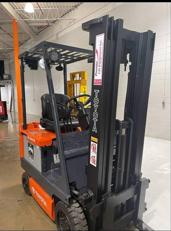 Front angle side view of refurbished 1996 Toyota 5FBCU15 vintage electric 4-wheel sit-down forklift showing fork tips, mast extension, and CSA certification decal during Ontario deployment
