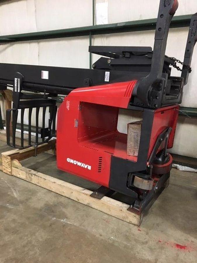 Rear-angle reverse view of Raymond 750DR32TT deep-reach forklift cradled on flatbed trailer for shipment, showing counterweight, rear wheels, and mast secured with transport straps during Brampton deployment