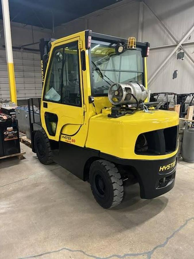 Rear side view of refurbished 2011 Hyster H80FT LP Gas forklift showing rear chassis, solid pneumatic tires, and safety lighting during Ontario deployment.