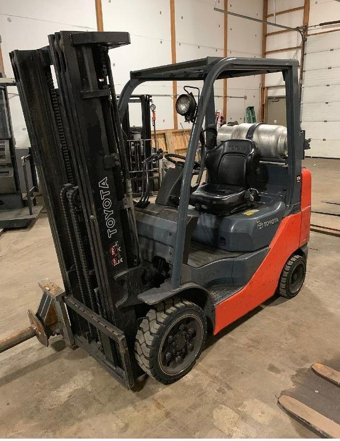 Front side view of refurbished 2013 Toyota 8FGCU25 LP gas forklift showing triple mast, carpet pole attachment, and solid cushion tires during Brampton deployment