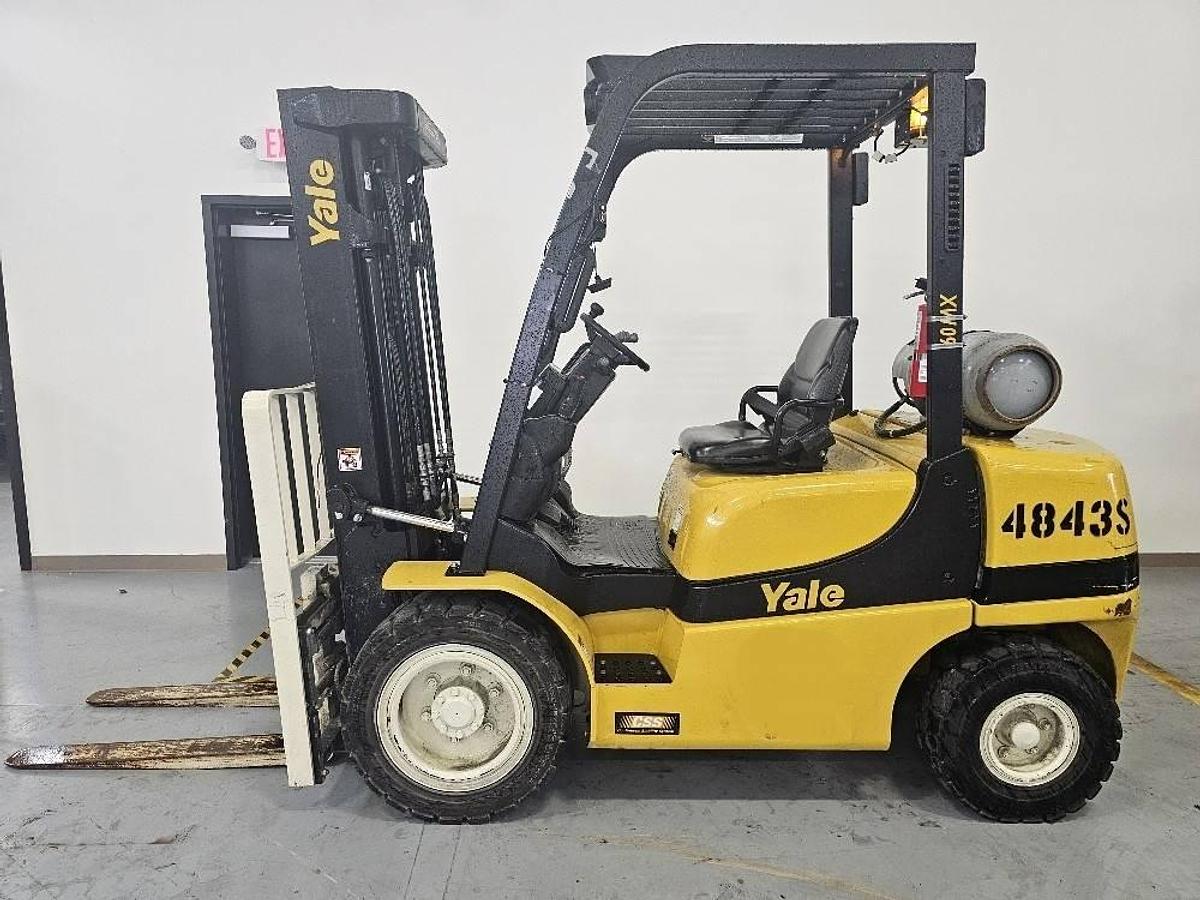 Side profile of refurbished 2018 Yale GLP060MXNEAE087 LPG pneumatic forklift showing 87/181 triple mast, chassis layout, solid pneumatic tires, and operator cab during Brampton deployment