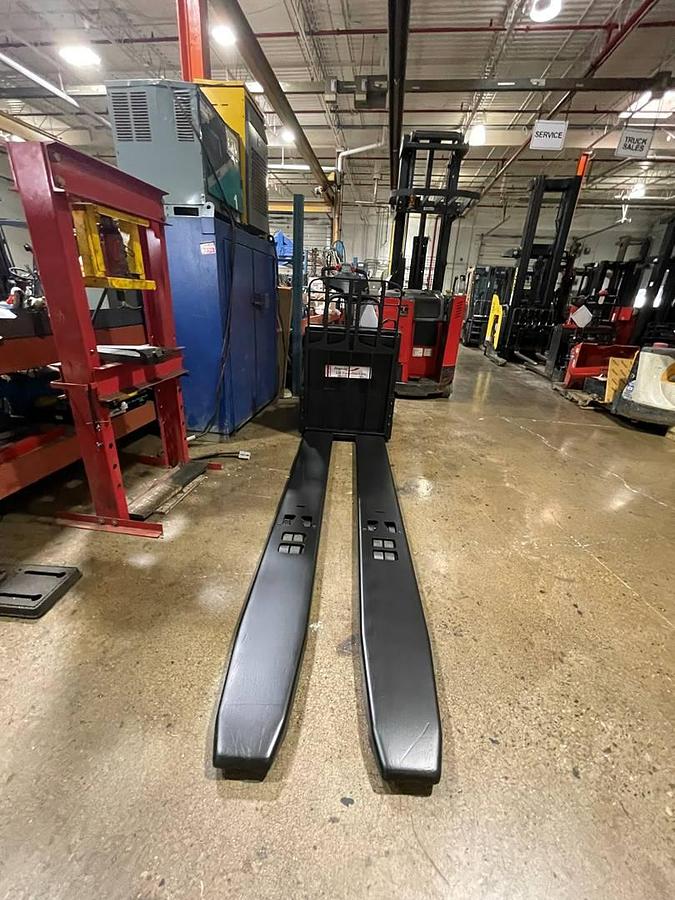 Front view of refurbished 2014 Raymond 8410 electric rider pallet truck showing 27" x 97" forks, fork heels, and front chassis panel during Toronto deployment