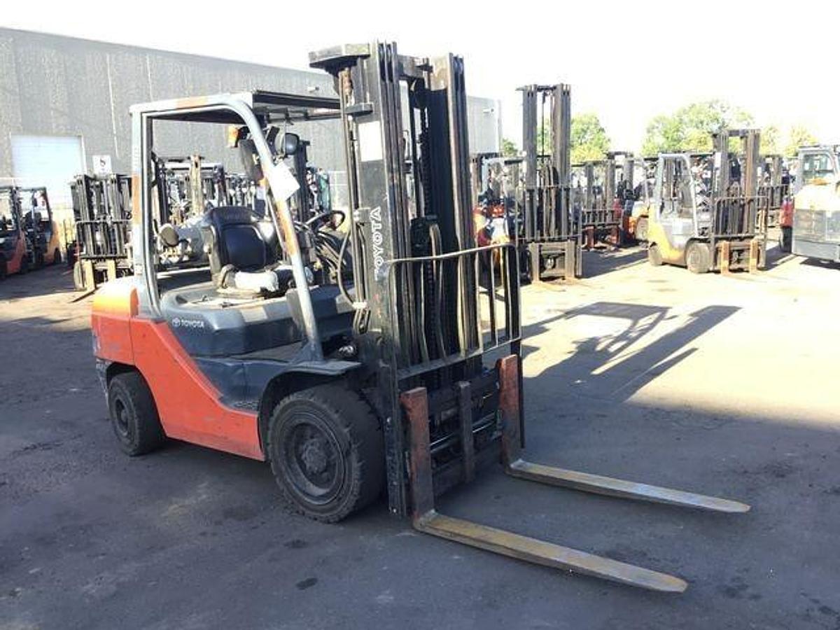 Opposite front side view of refurbished 2016 Toyota 8FGU30 LP gas forklift showing mast, forks, operator cab, and solid tire chassis during Brampton deployment