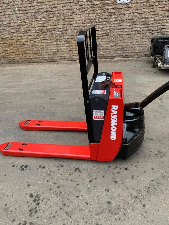 Side view of refurbished 2014 Raymond 102T-F45L electric walkie pallet truck showing battery compartment, tiller arm, and chassis frame during Oakville deployment