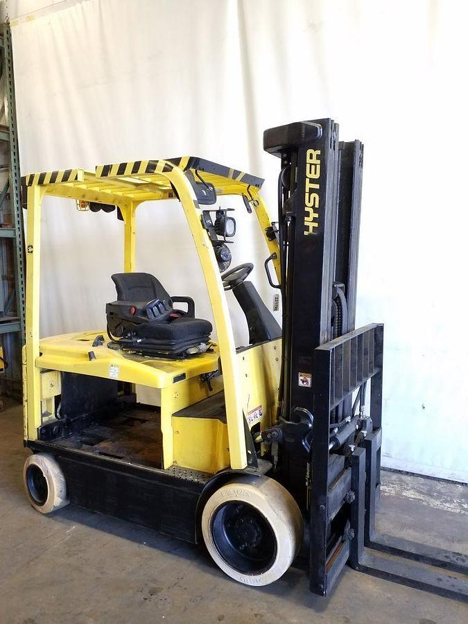 Side view of refurbished 2015 Hyster E70XN electric forklift showing 54" forks, side shift fork positioner, new battery compartment, solid tires, and CSA certification decal during Ontario deployment.