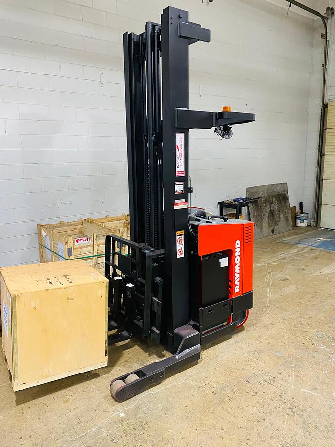 Front angled view showing mast rails and 42” fork tips with charger in box