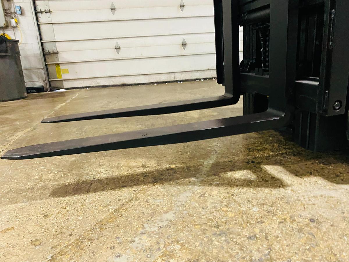 Side view of electric forklift showing forks mounted on carriage with factory-installed side shift, mast rails and CSA safety decals visible during Brampton deployment