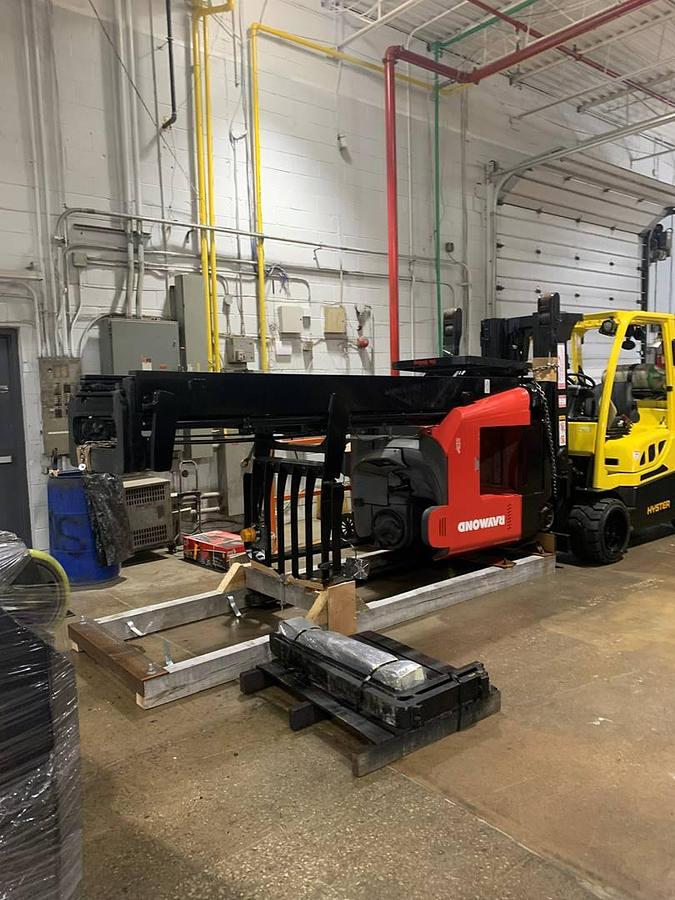 Angled view of refurbished 2019 Raymond 772-R45TT electric reach truck laid down and cradled for shipment, showing mast tilt, fork carriage, and chassis secured for transport during Toronto deployment