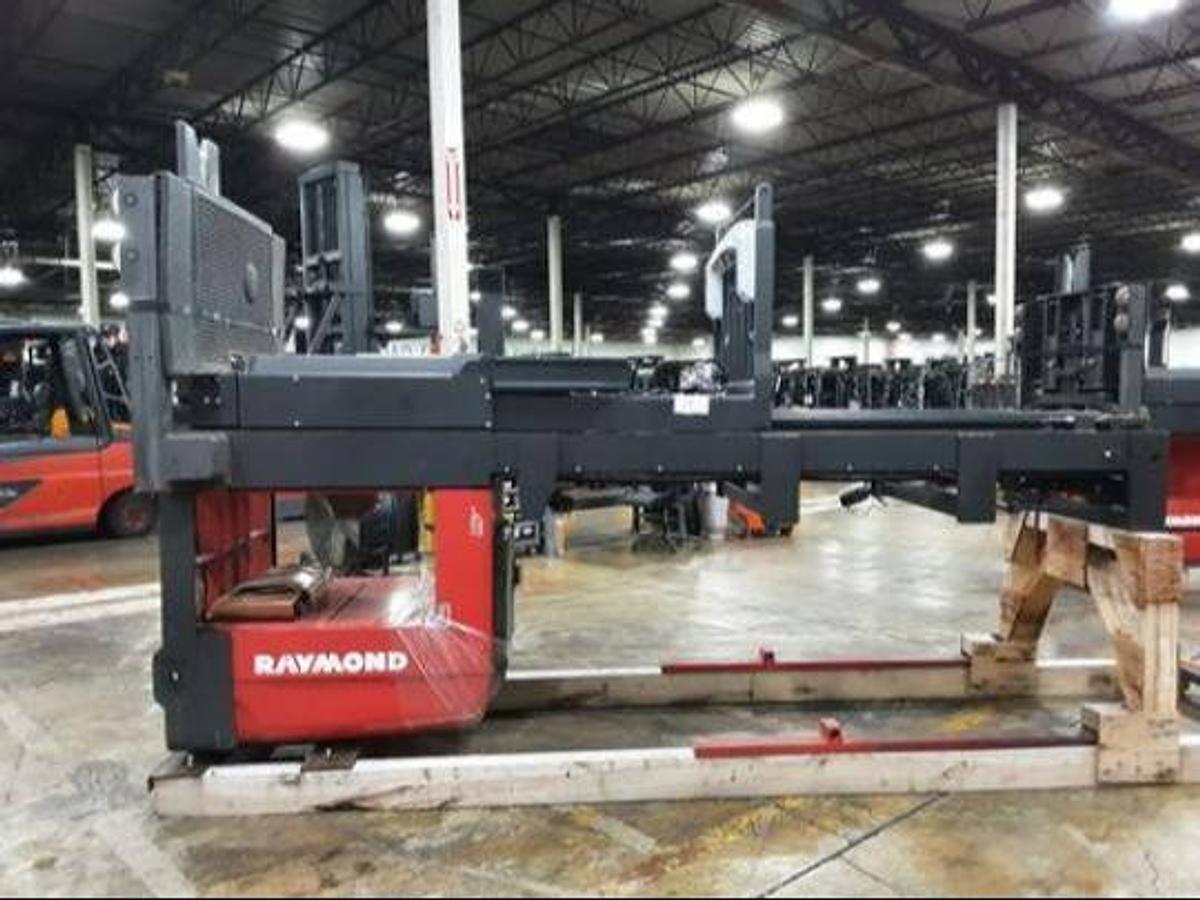 Side view of refurbished 2017 Raymond 560-OPC30TT electric order picker laid down and cradled, showing chassis frame, mast rails, and platform base with minimal battery visibility during Concord deployment